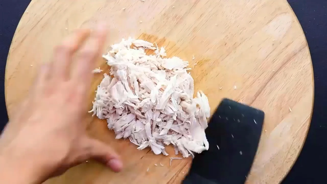 Adding shredded chicken to the salad bowl.