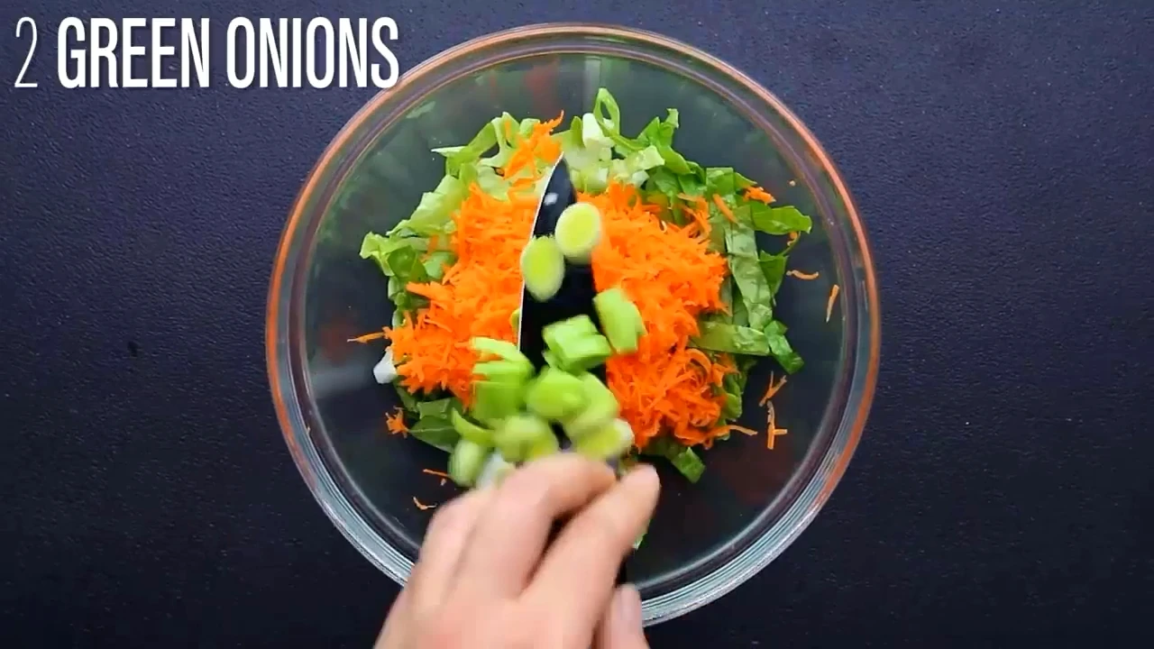 Adding green onions to chicken lettuce salad.