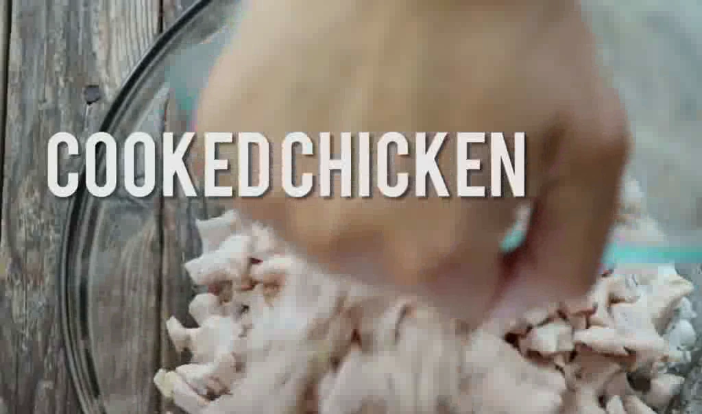 Adding chopped cooked chicken to the creamy chicken salad mixture.