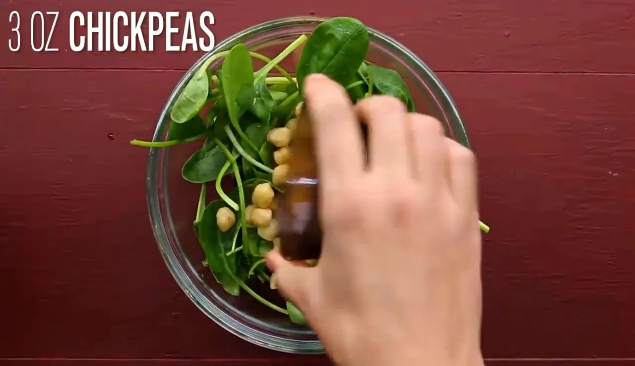 Adding spinach and chickpeas to a bowl