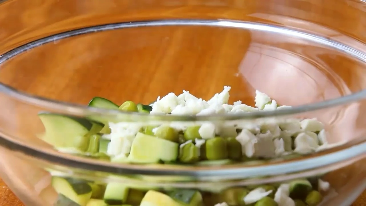 Adding peas and feta to cucumber avocado salad.