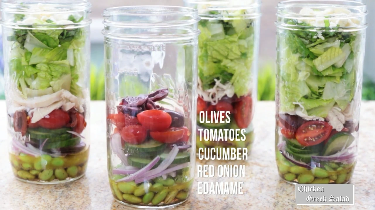 Adding tomatoes and olives to Greek salad jars.