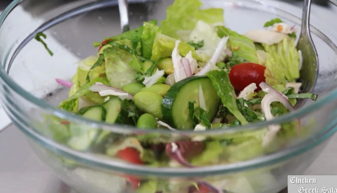 Dumping a jar of Greek salad into a bowl and tossing it.