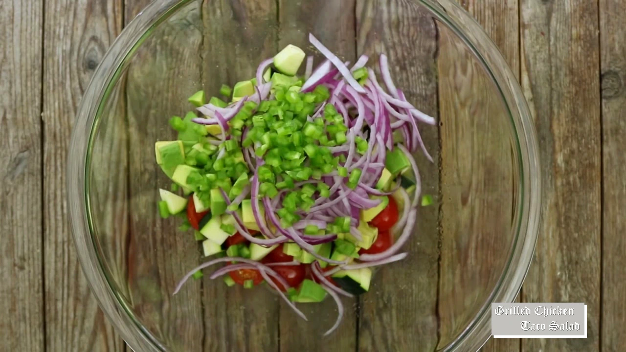 Tomatoes, zucchini, avocado, red onion, and jalapeno in a bowl for grilled chicken taco salad.