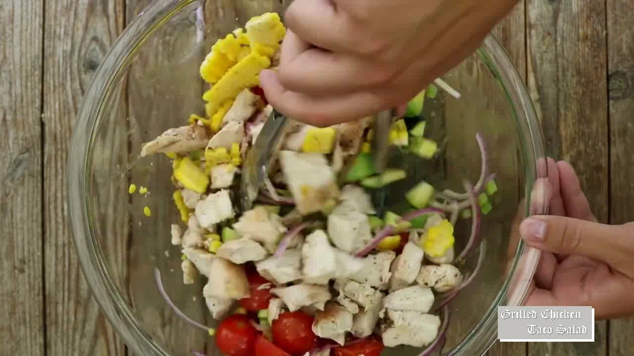 Adding grilled corn to chicken taco salad.