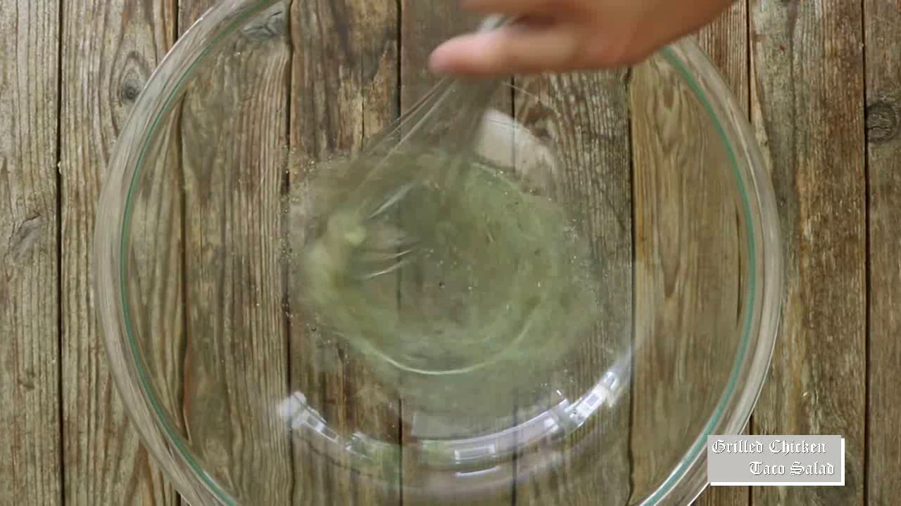 Whisking lime dressing for grilled chicken taco salad.