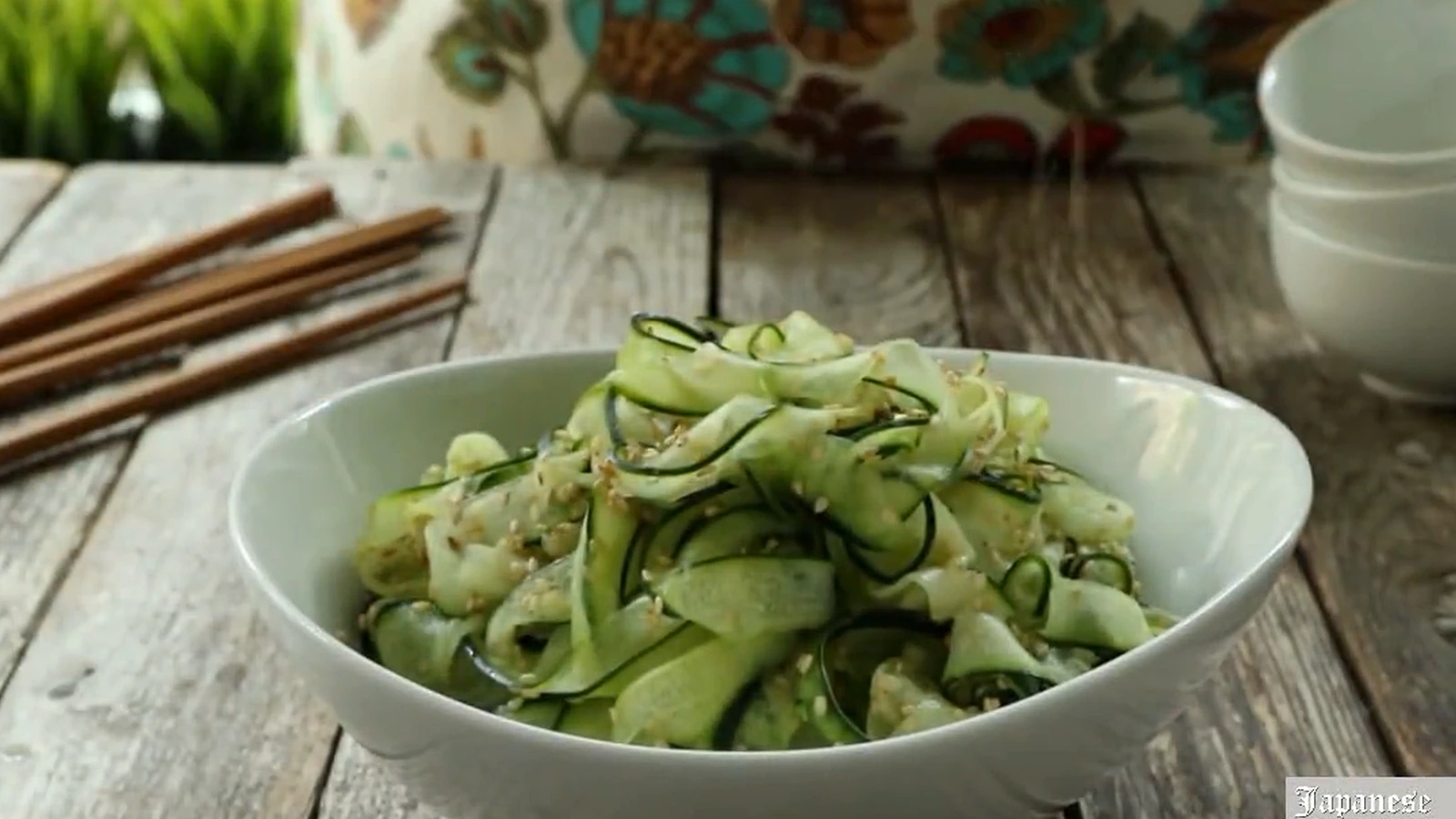 Japanese cucumber salad in a white bowl with sesame seeds on top.