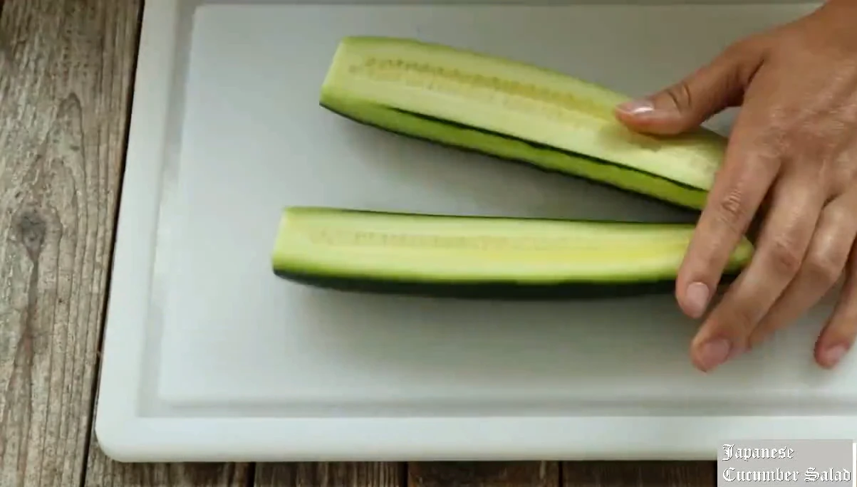 Peeling stripes and splitting the cucumber lengthwise.