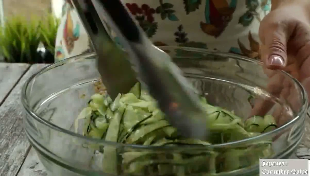 Tossing cucumber ribbons in dressing.