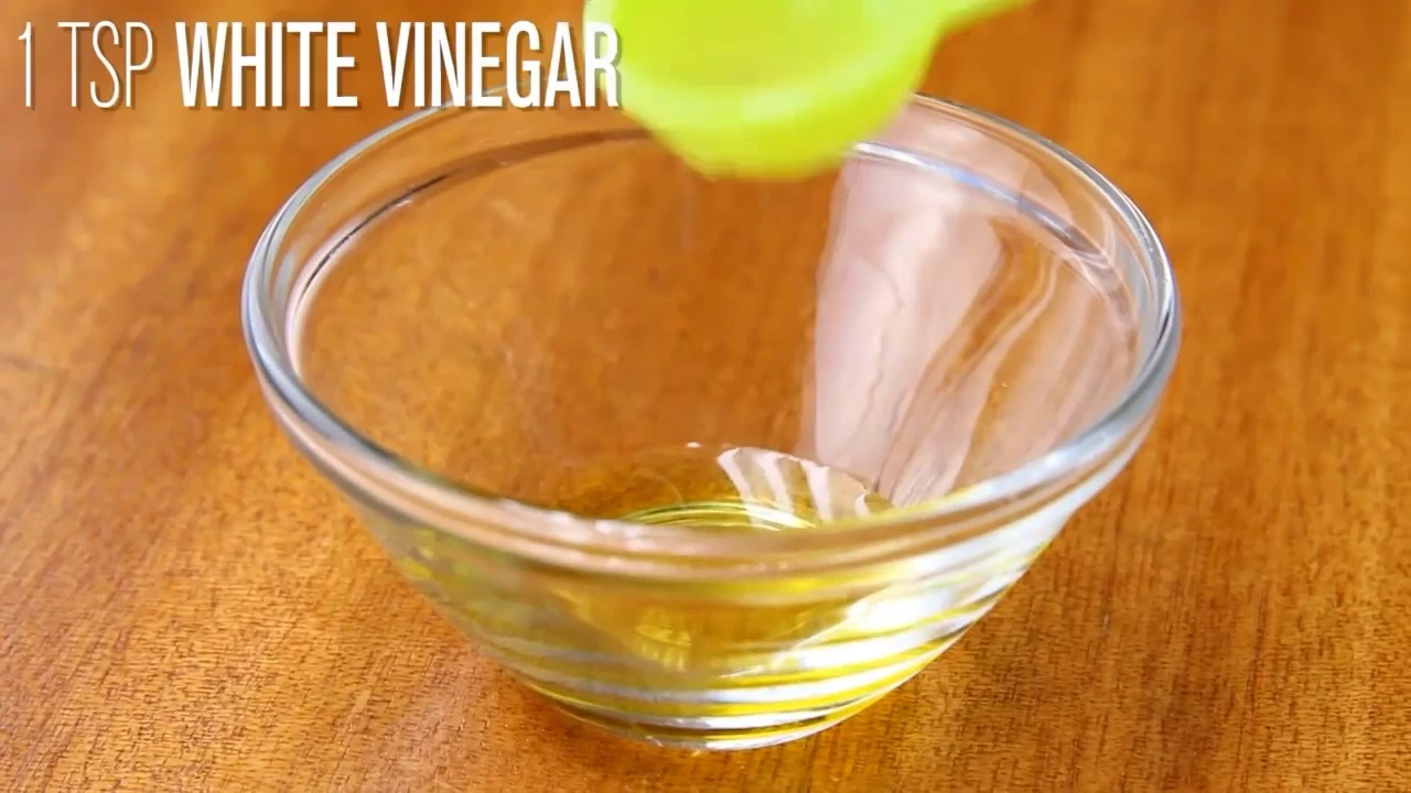 Adding vinegar to a small bowl for dressing.