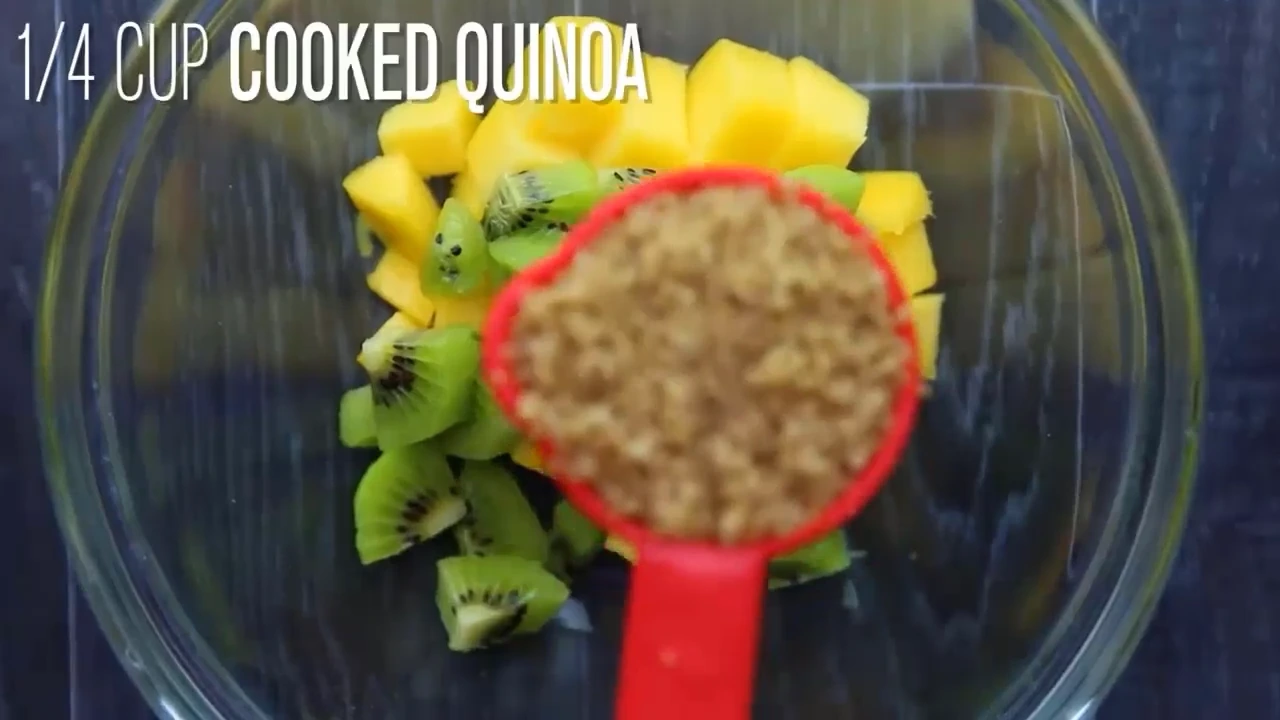Adding cooked quinoa to fruit for quinoa fruit salad.
