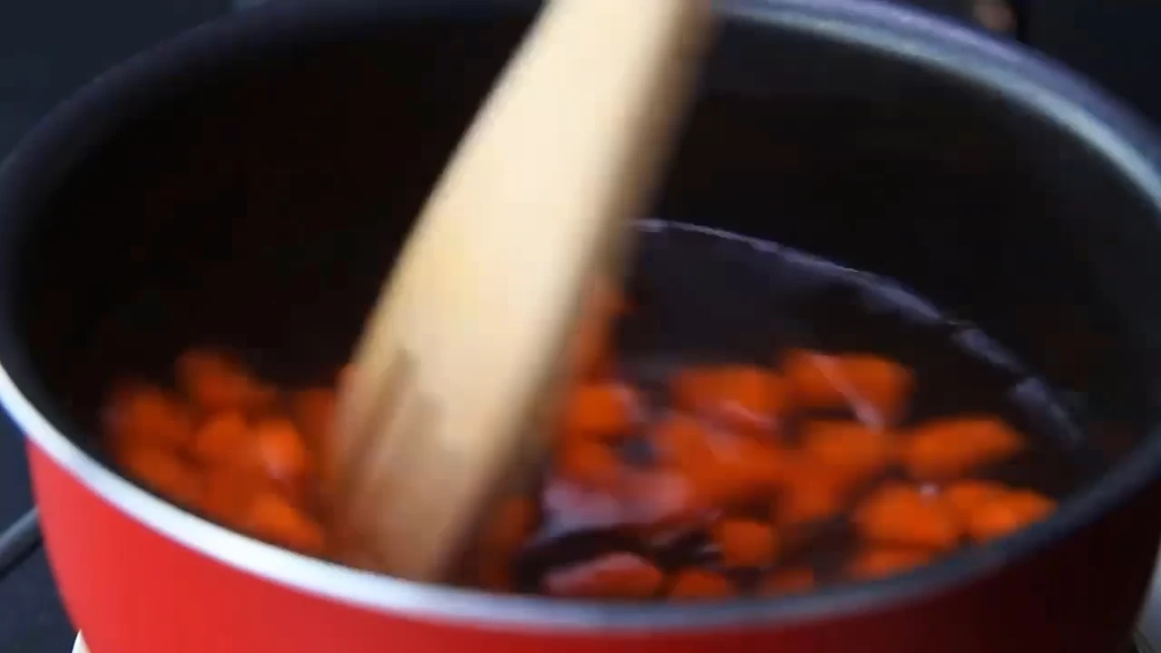Cooking carrot in a pot for quinoa salad.