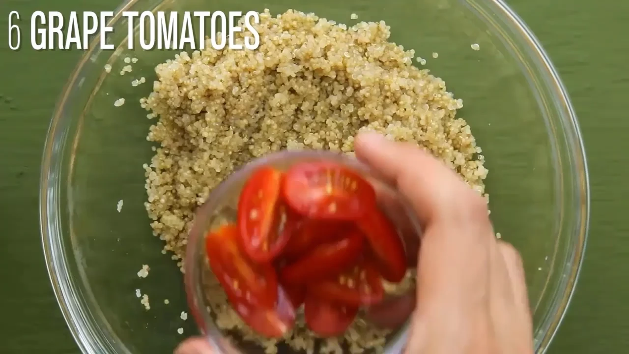 Adding grape tomatoes to chilled quinoa for quinoa salad with avocado.