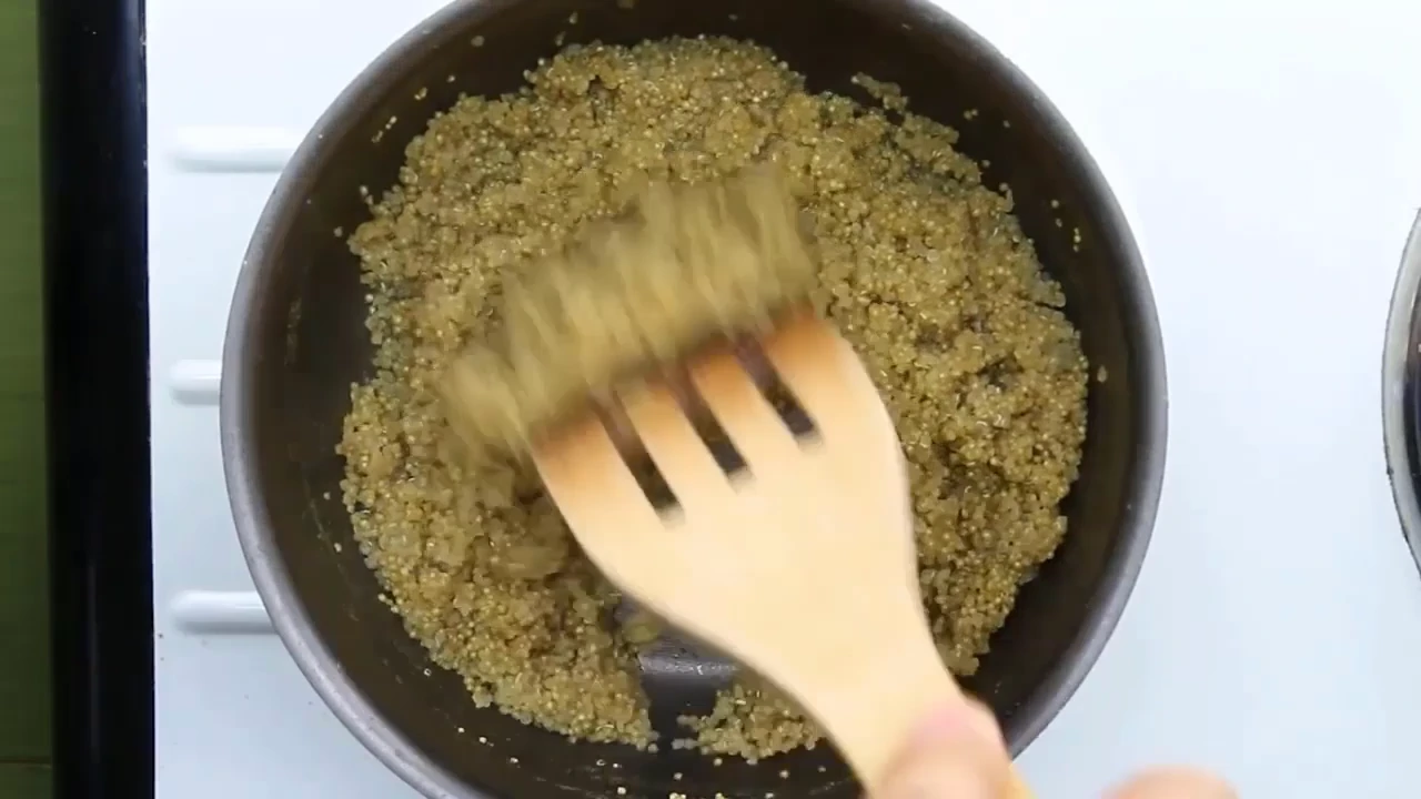 Fluffing cooked quinoa for quinoa salad with avocado.
