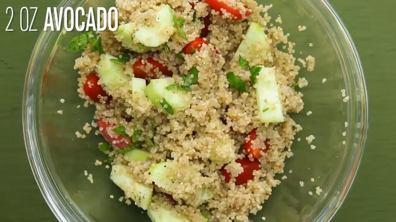 Adding avocado to quinoa salad with avocado.