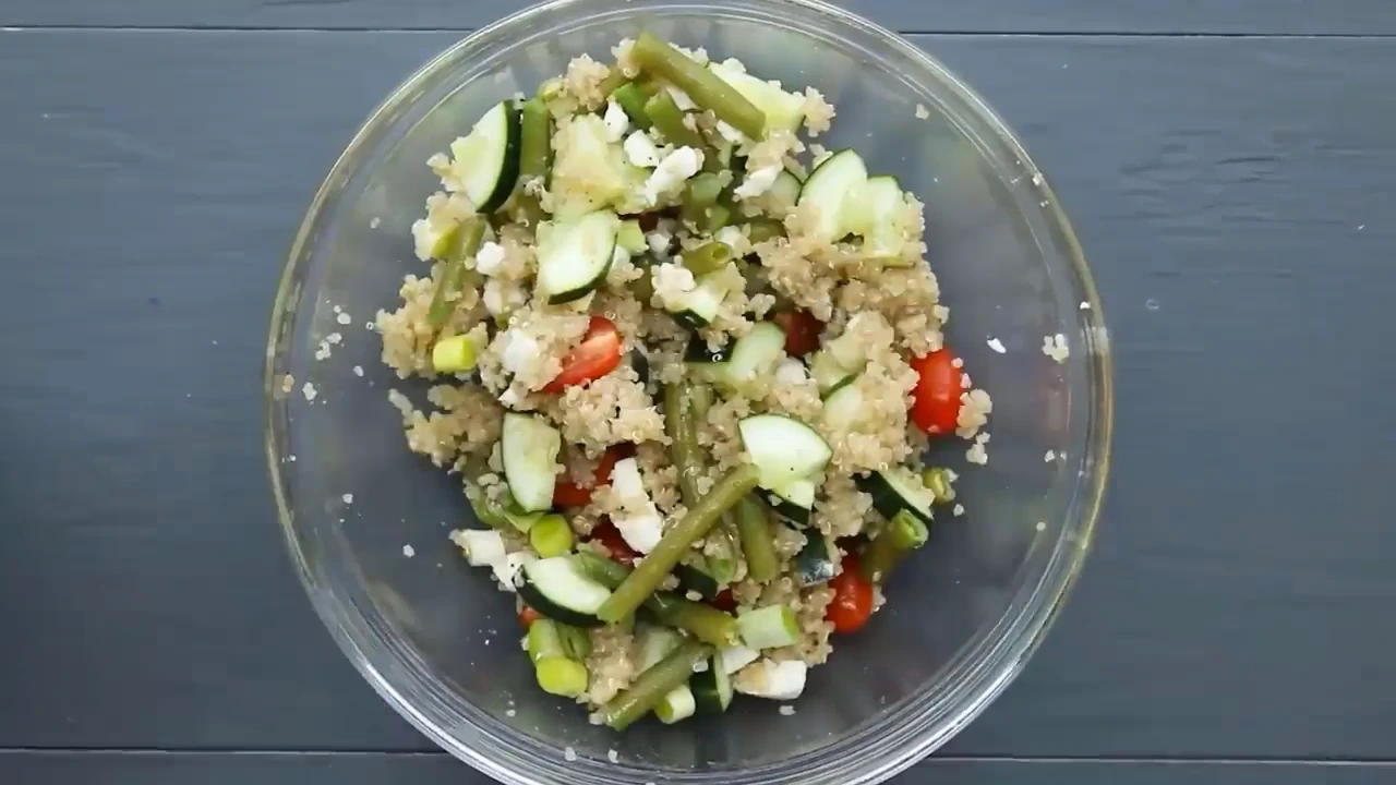 Tossing quinoa salad with feta in a bowl.
