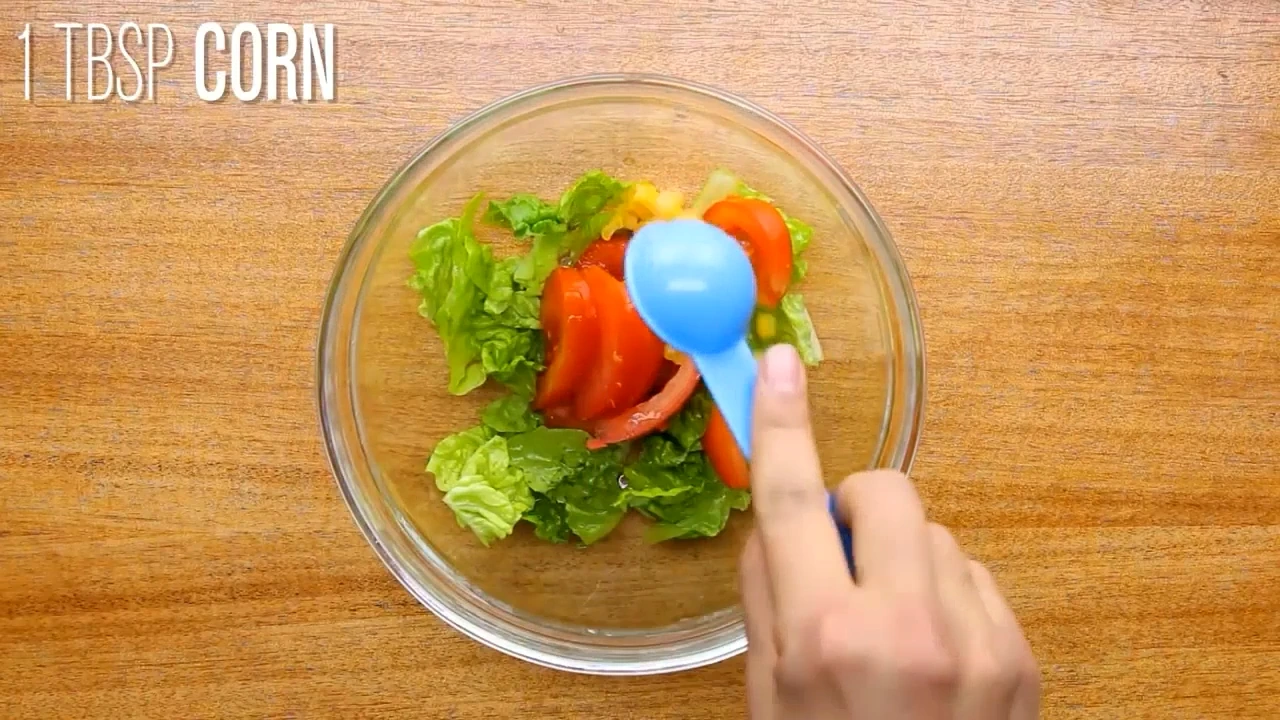 Adding corn to roasted chicken salad.