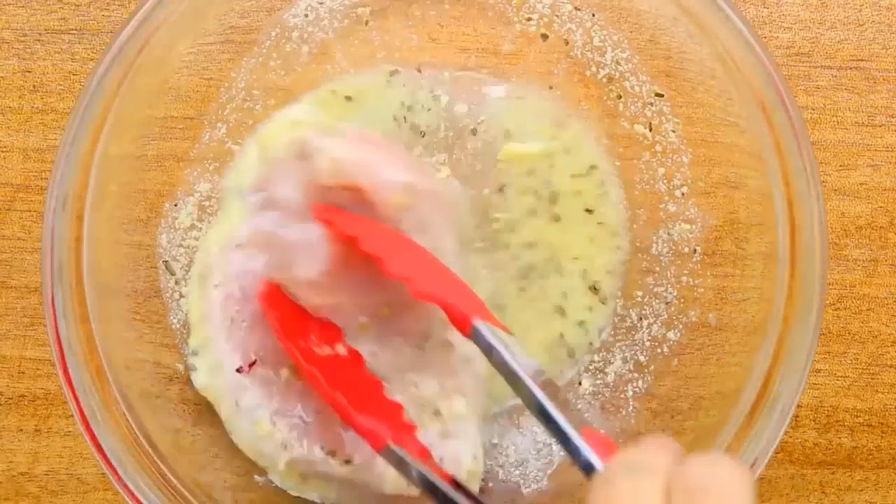 Coating chicken breast in lemon mustard marinade.