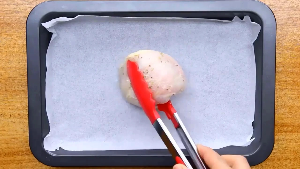 Transferring coated chicken to a parchment-lined tray.