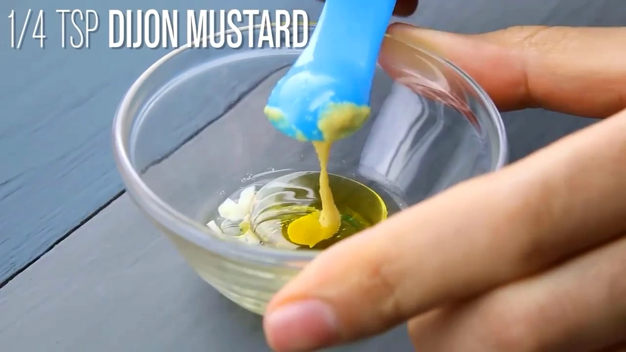 Dijon mustard being added to the dressing bowl