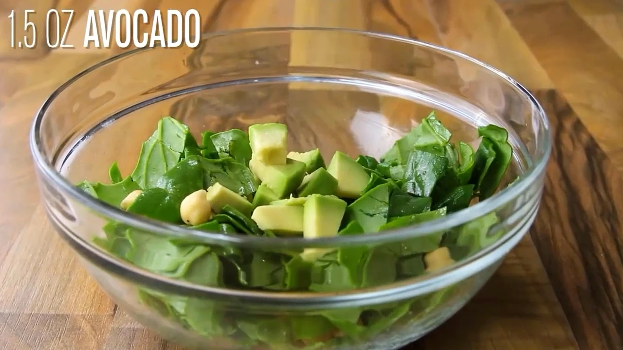 Avocado being added to the spinach chickpea salad