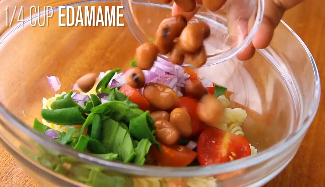 Adding red onion and edamame to spinach pasta salad