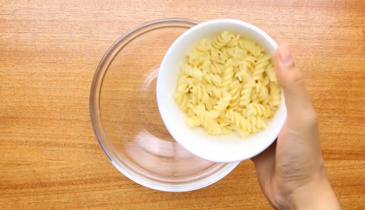 Transferring cooked fusilli to a bowl