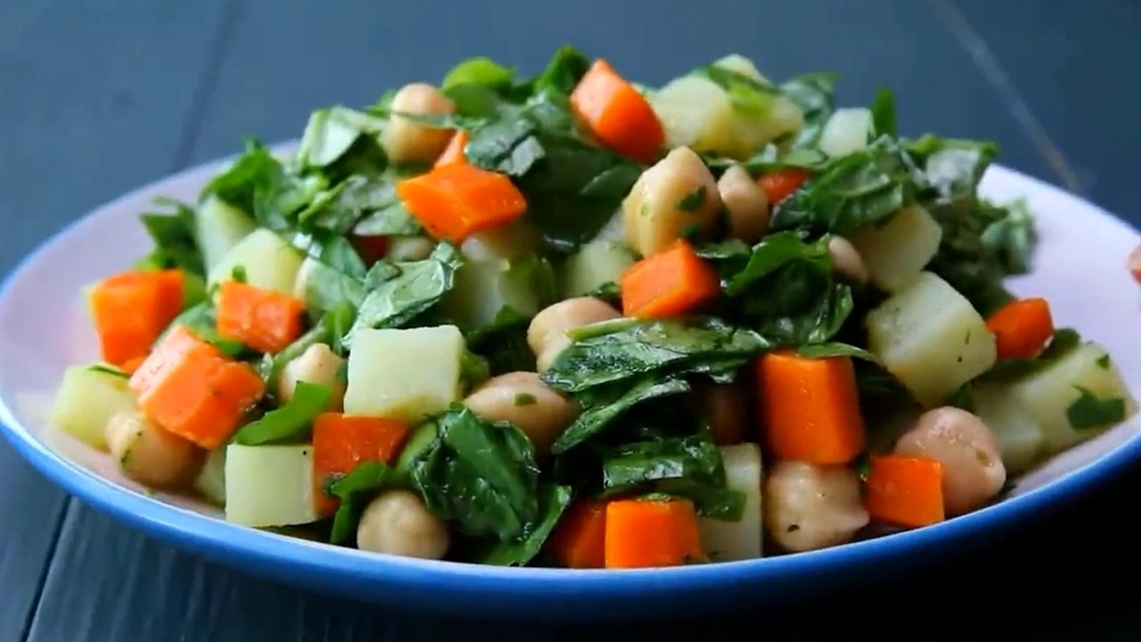 Spinach potato salad with carrot and chickpeas on a plate.