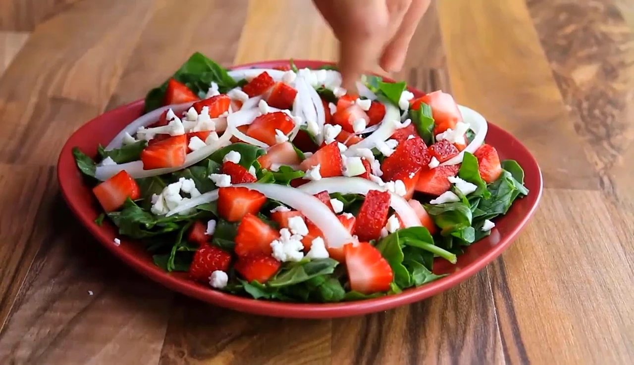Adding onion and feta to strawberry spinach salad