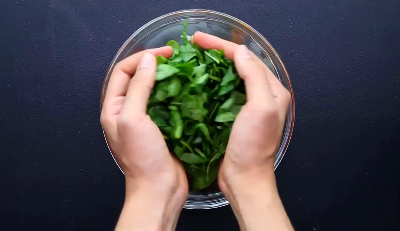 Adding chopped spinach to a mixing bowl