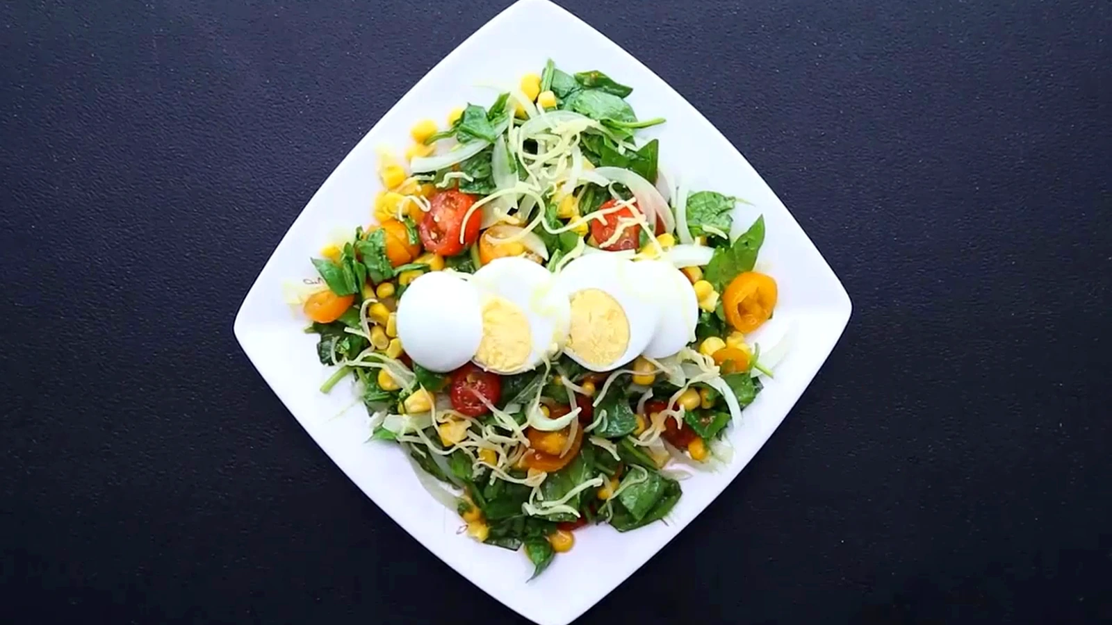 Summer spinach and corn salad topped with sliced egg and cheddar