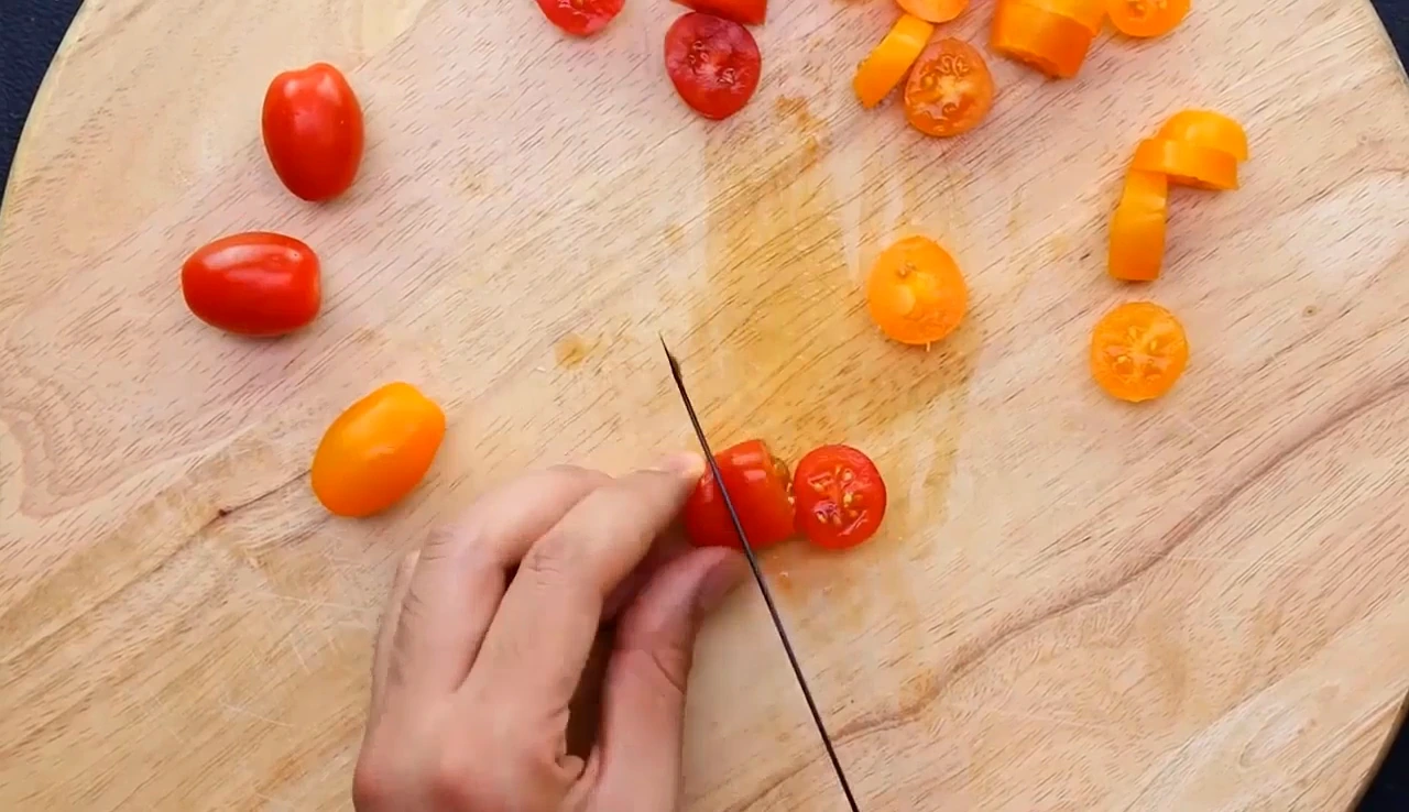 Halving grape tomatoes for summer spinach and corn salad