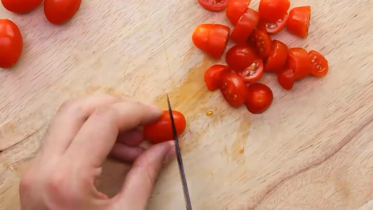Chopping cherry tomatoes on a board.