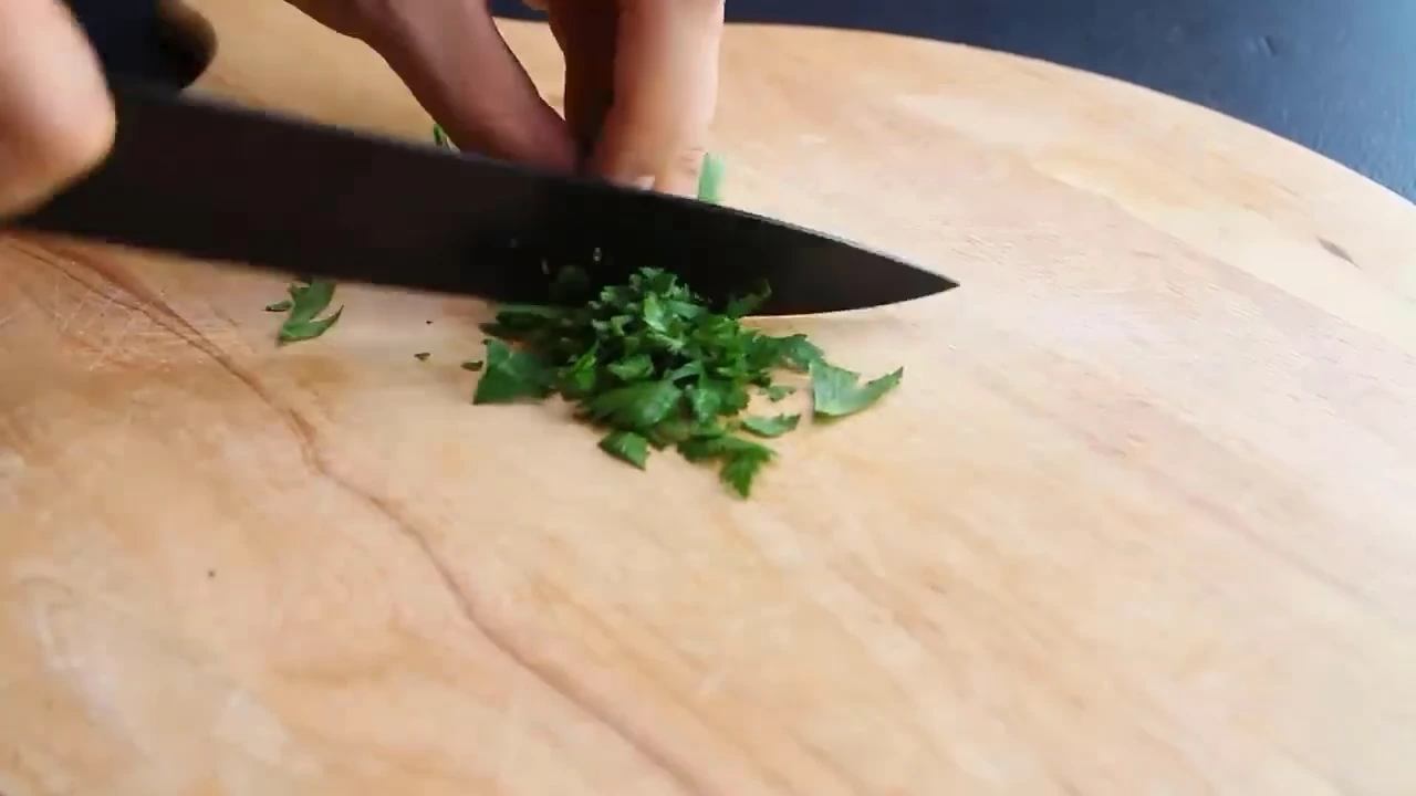 Chopping parsley on a cutting board.