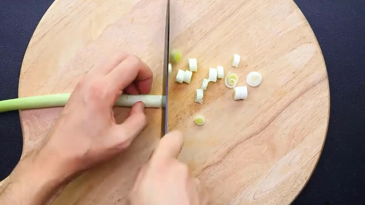 Slicing green onion on a board.