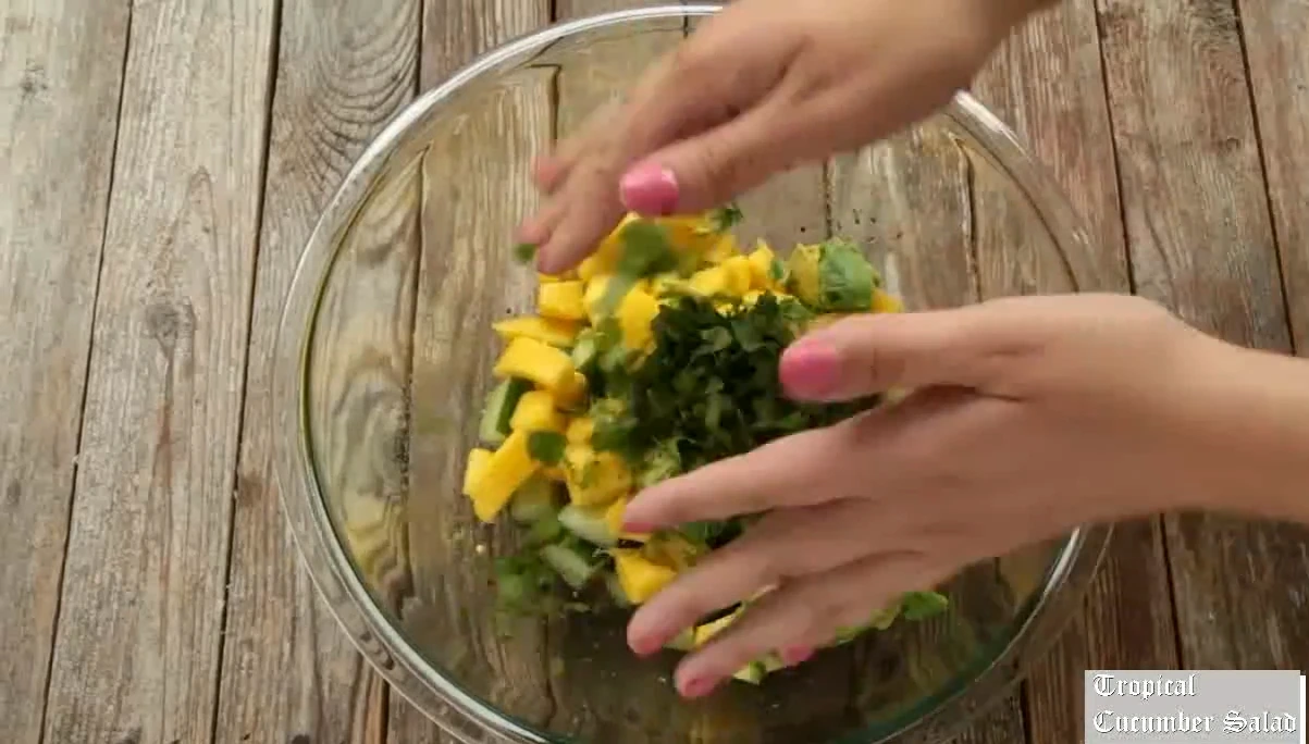 Adding cucumber, mango, avocado, and cilantro to the tropical dressing.