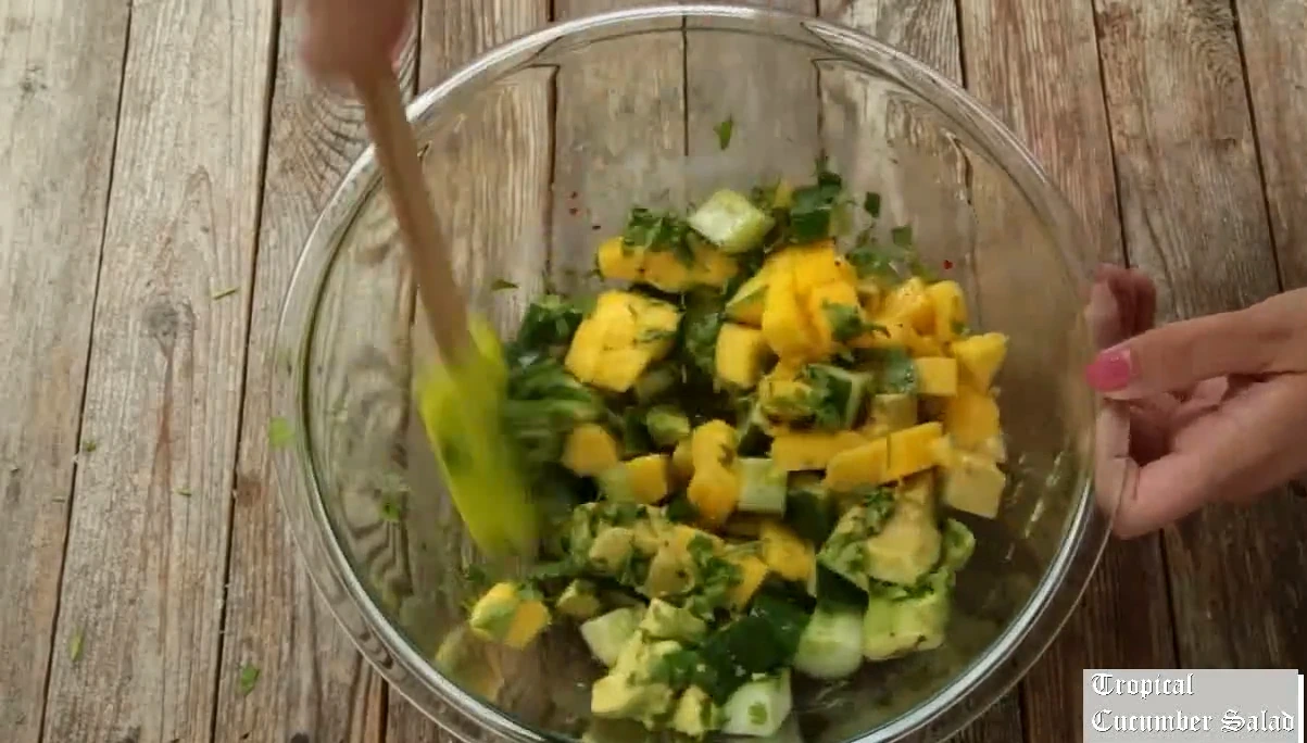 Tossing tropical cucumber salad gently.