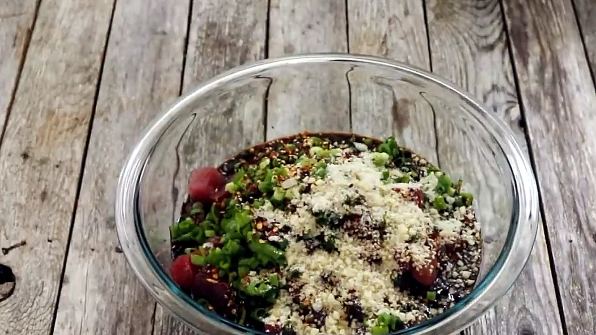 ahi poke ingredients layered in a glass mixing bowl before stirring