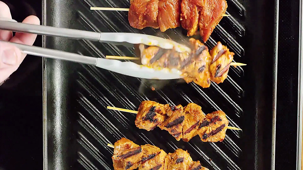 Grilled pork skewers with charred marks after flipping