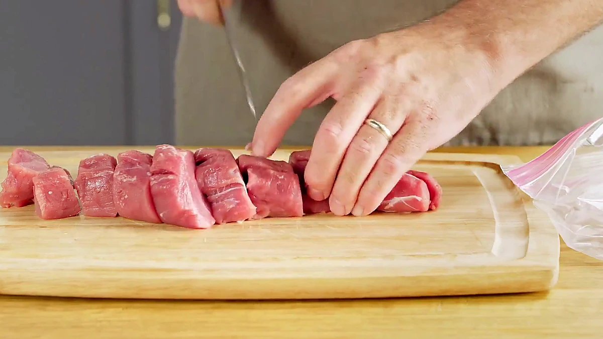 Pork tenderloin being cut into chunks for skewers