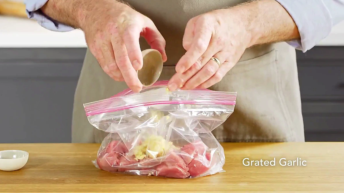 Grated garlic added to pork in a bag