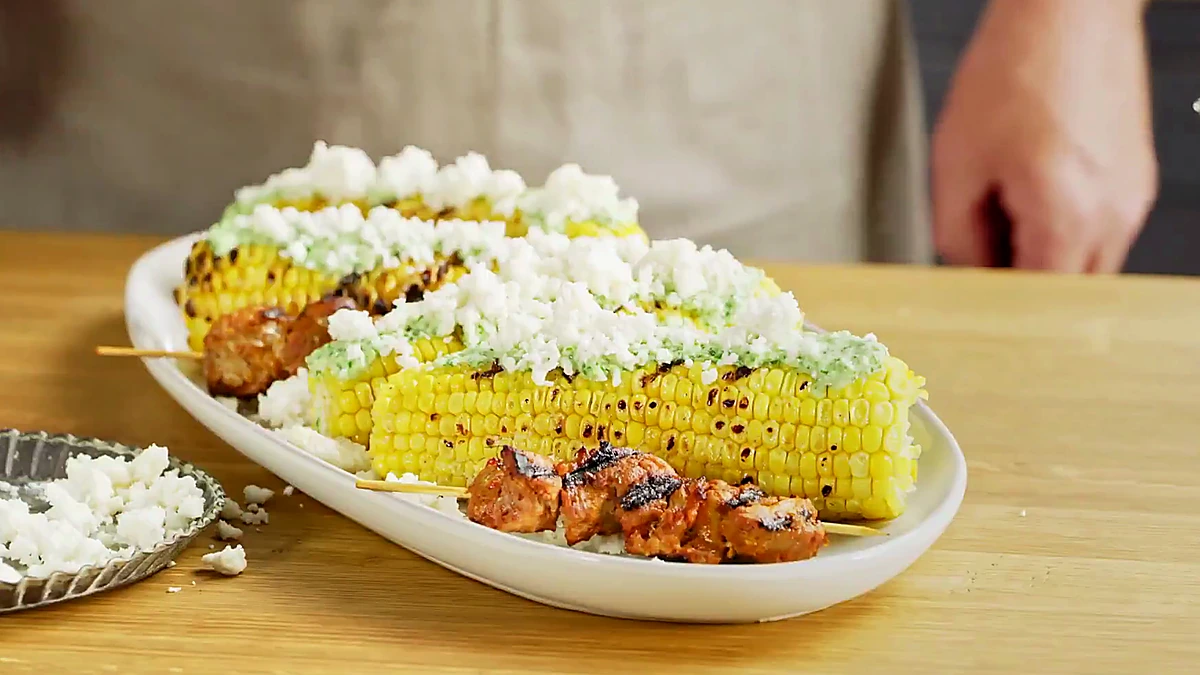 Close angle of aji verde pork skewers with grilled corn