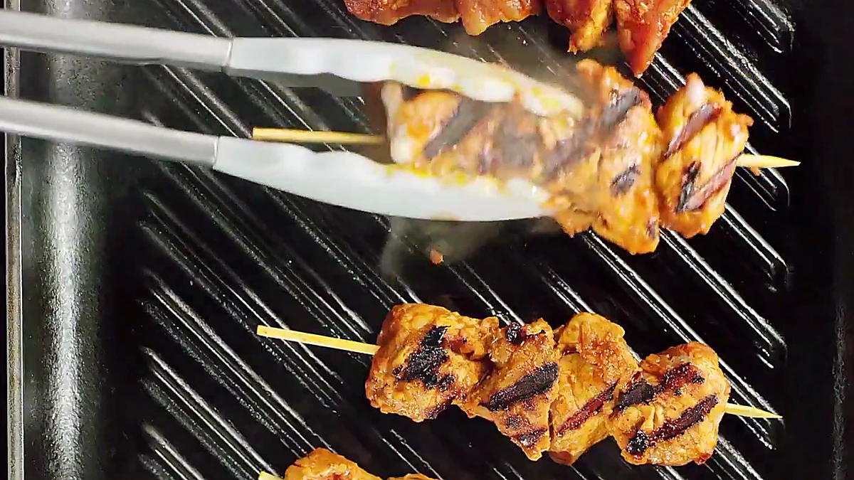 Grilled pork skewers with char marks on a grill pan