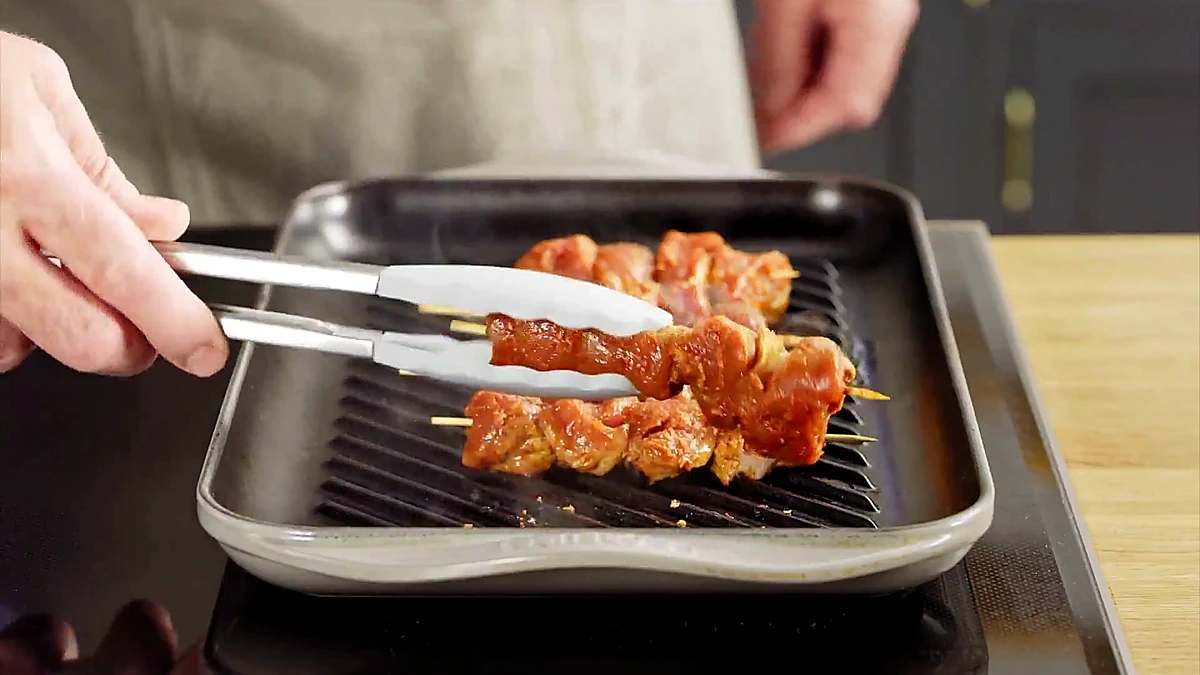 Pork skewers cooking on a grill pan