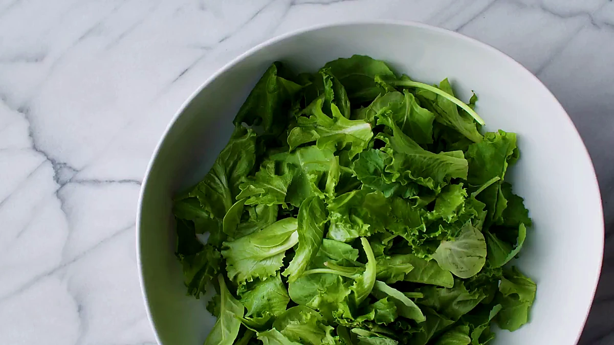 Mixed greens in a white serving bowl