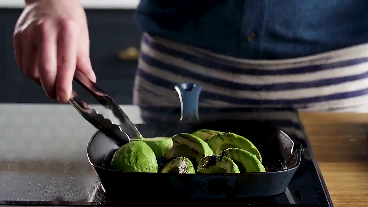 Grilled avocado pieces turned with tongs