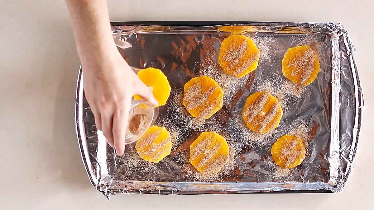 Orange slices sprinkled with cinnamon sugar on a sheet pan