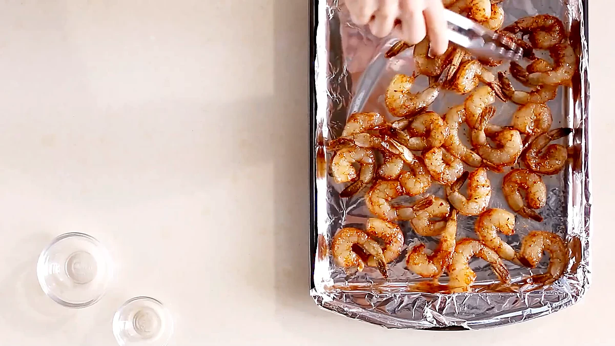 Seasoned shrimp arranged on a foil lined baking sheet