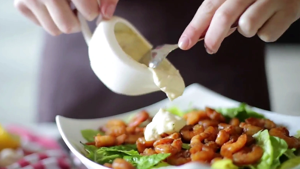 Caesar dressing spooned over shrimp salad