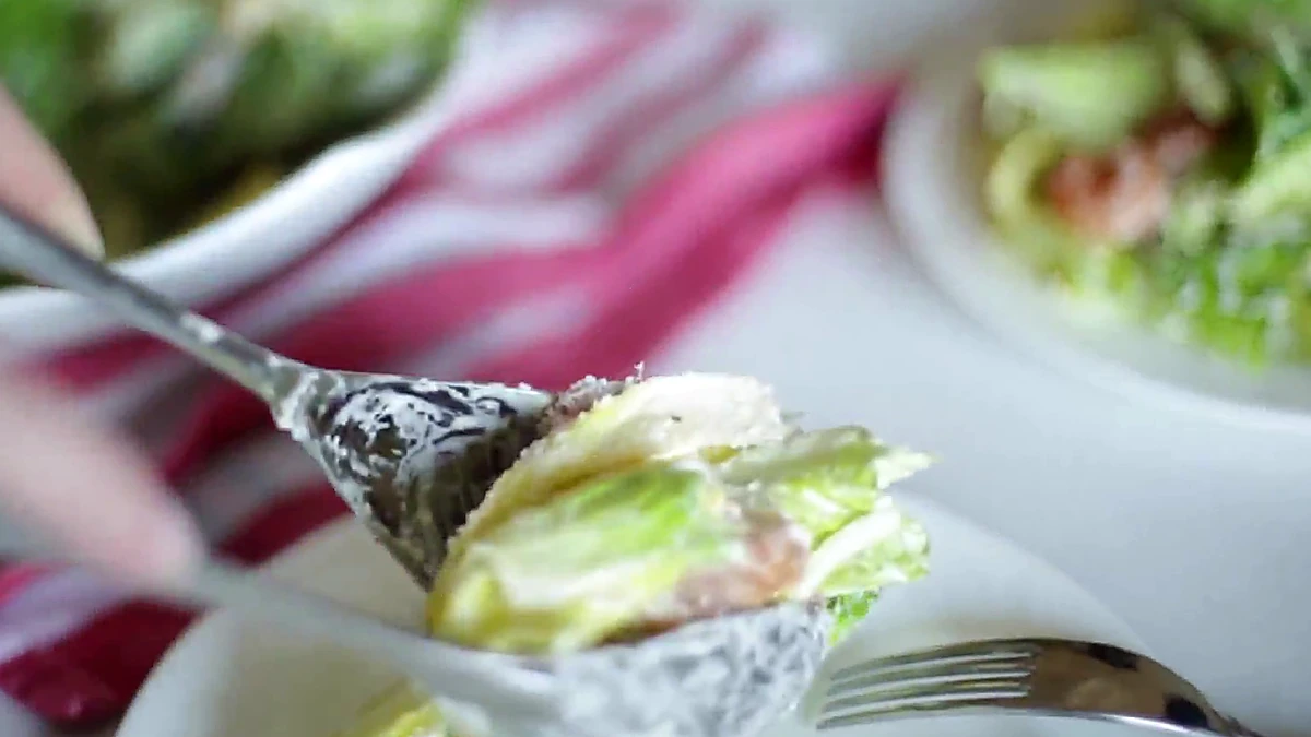 A bite of grilled shrimp Caesar salad being served